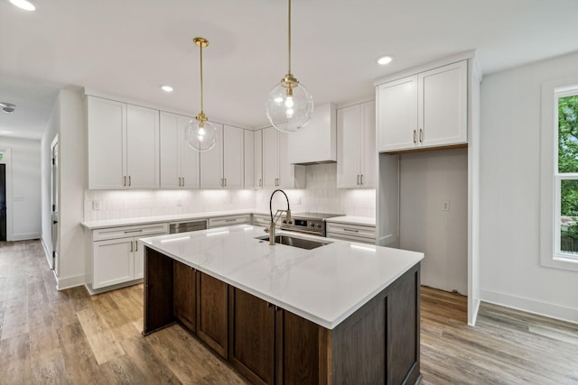 kitchen with sink, white cabinets, pendant lighting, and a kitchen island with sink