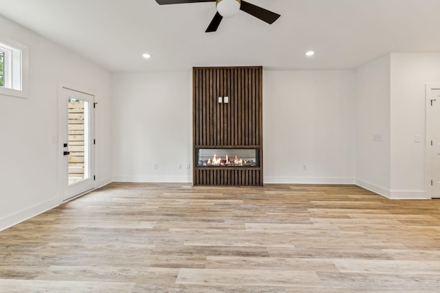 unfurnished living room with ceiling fan, light wood-type flooring, and a multi sided fireplace