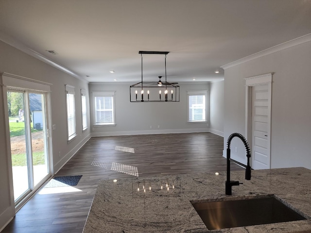 kitchen featuring a healthy amount of sunlight, decorative light fixtures, stone countertops, ornamental molding, and sink