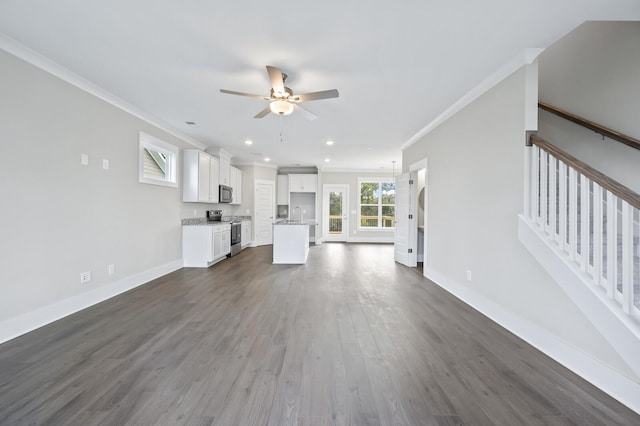 unfurnished living room featuring ceiling fan, dark wood-type flooring, sink, and crown molding