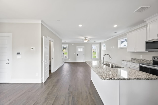 kitchen with white cabinets, stainless steel appliances, an island with sink, sink, and light stone counters