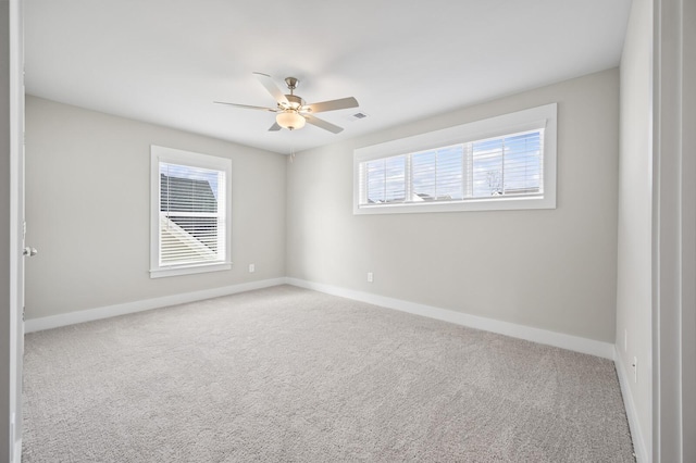 carpeted empty room featuring ceiling fan and a wealth of natural light