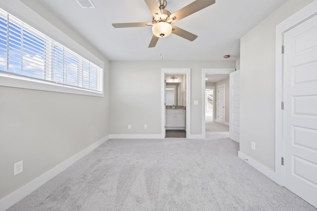 unfurnished bedroom featuring ensuite bathroom, light colored carpet, and ceiling fan