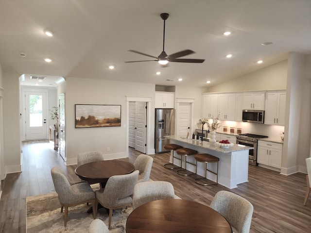 dining area with ceiling fan, vaulted ceiling, dark hardwood / wood-style flooring, and sink