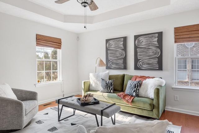 living room with ceiling fan, hardwood / wood-style floors, and a tray ceiling