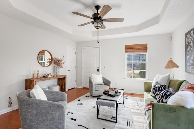 living room with ceiling fan, hardwood / wood-style floors, a tray ceiling, and a textured ceiling