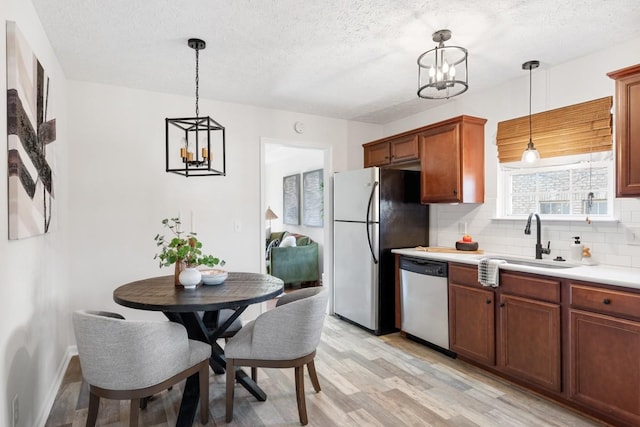 kitchen featuring a notable chandelier, appliances with stainless steel finishes, pendant lighting, and sink