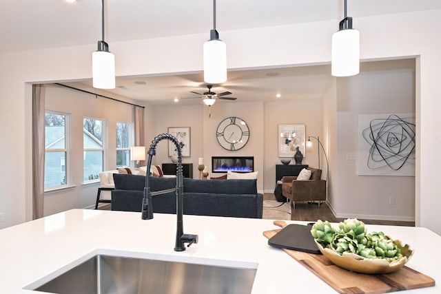 kitchen featuring hanging light fixtures, ceiling fan, and sink