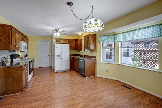 kitchen with ceiling fan with notable chandelier, light hardwood / wood-style flooring, hanging light fixtures, and white appliances