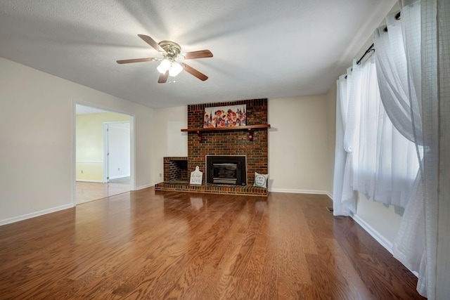 unfurnished living room featuring ceiling fan, wood-type flooring, a fireplace, and a textured ceiling