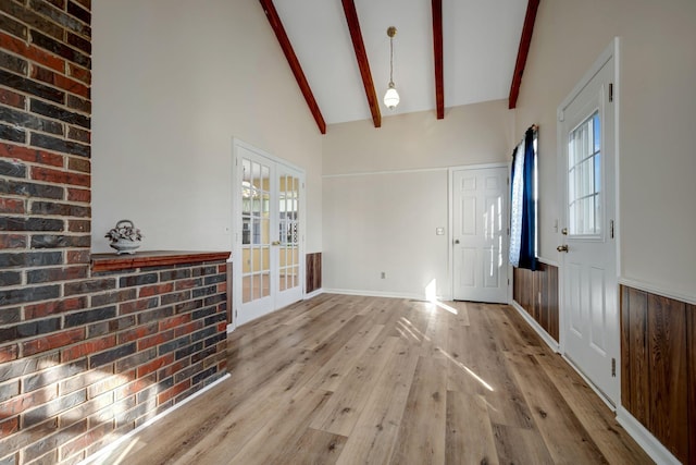 interior space with beamed ceiling, wooden walls, light wood-type flooring, high vaulted ceiling, and french doors