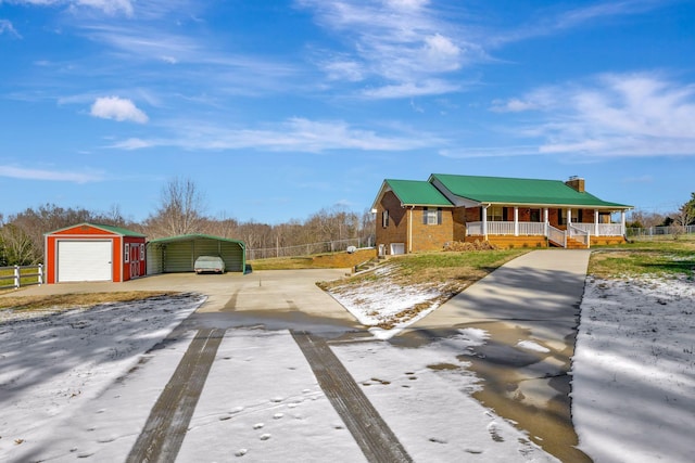 view of front of property featuring covered porch, a garage, an outdoor structure, and a carport