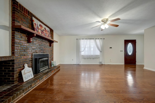 unfurnished living room featuring a textured ceiling, ceiling fan, wood-type flooring, and a brick fireplace