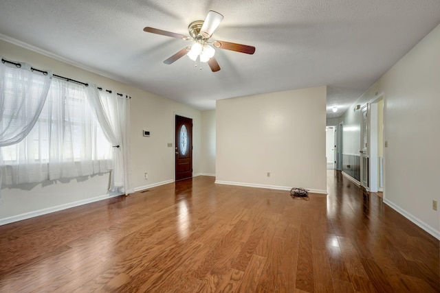 empty room with a textured ceiling, ceiling fan, and wood-type flooring