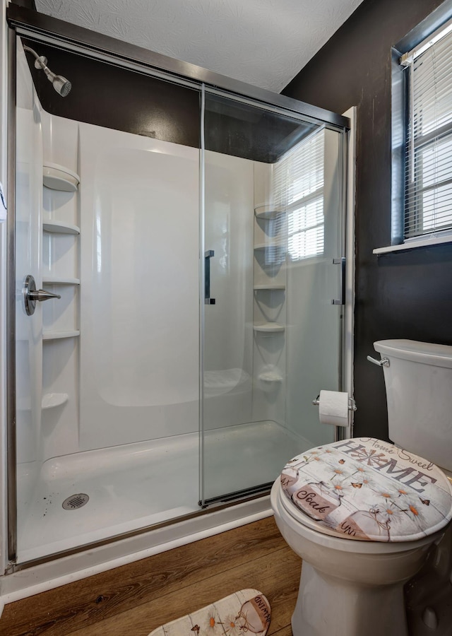 bathroom featuring toilet, wood-type flooring, and an enclosed shower