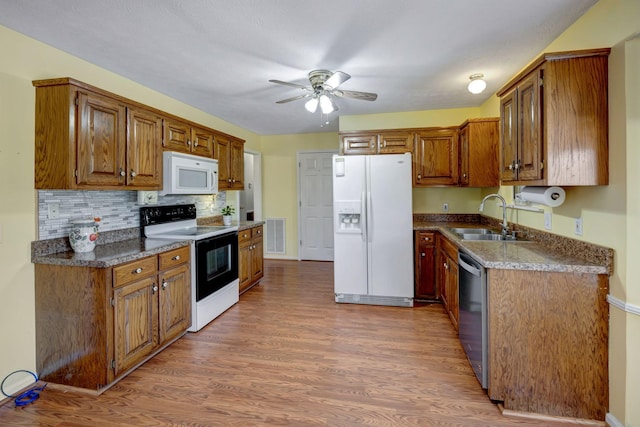 kitchen featuring ceiling fan, white appliances, dark hardwood / wood-style flooring, dark stone countertops, and sink