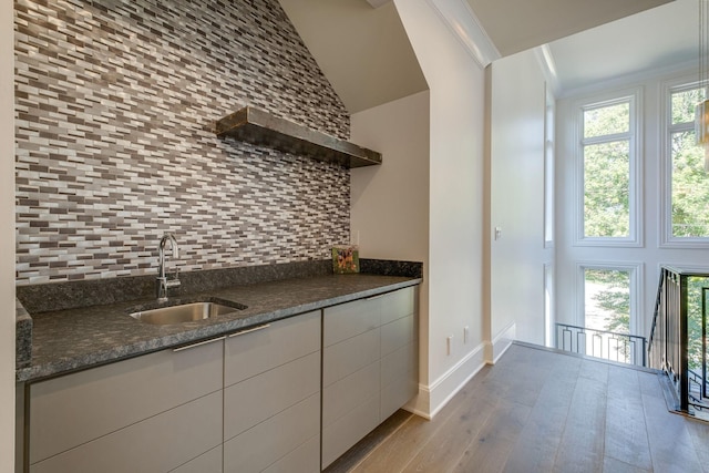 kitchen with backsplash, sink, ornamental molding, white cabinets, and dark stone counters