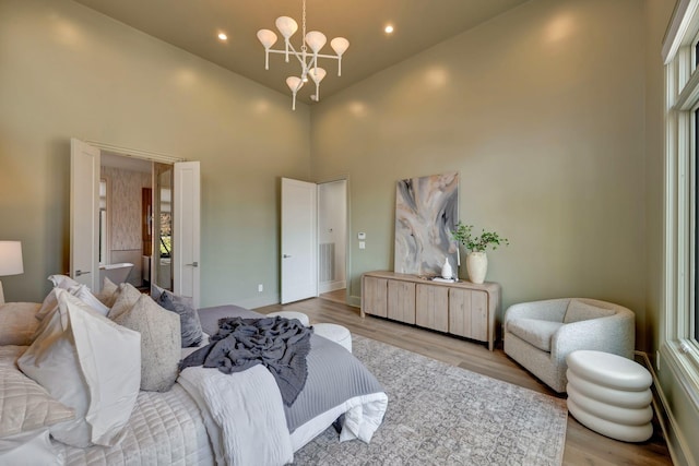 living room with a notable chandelier, light hardwood / wood-style floors, and high vaulted ceiling