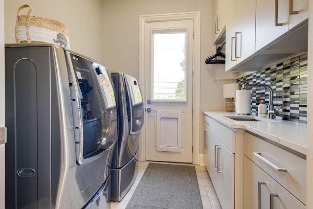 clothes washing area with cabinets, sink, and washing machine and clothes dryer