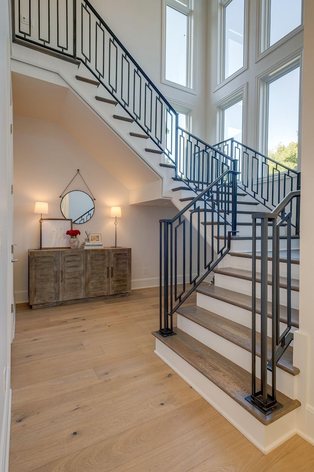 stairs with a towering ceiling and hardwood / wood-style flooring