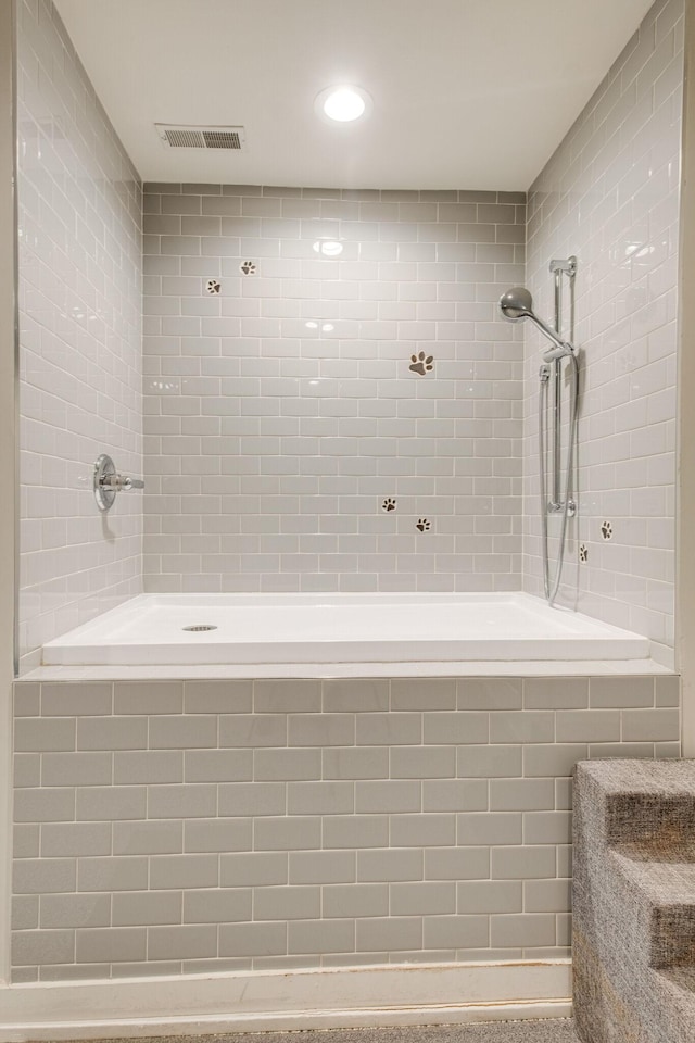 bathroom with a tile shower and tile walls