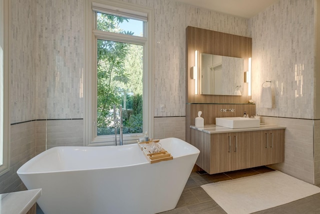 bathroom featuring a wealth of natural light, tile patterned flooring, a bathtub, and vanity