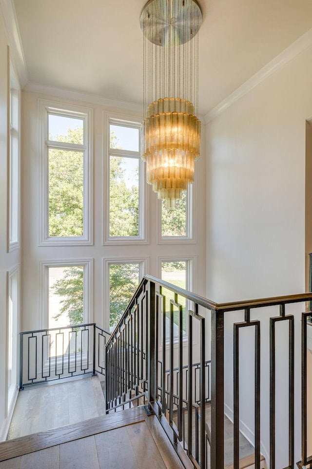 stairs featuring an inviting chandelier, ornamental molding, and a towering ceiling