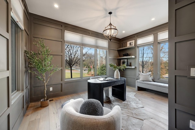 office space featuring light wood-type flooring, built in features, and a notable chandelier