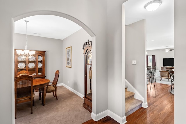 interior space with ceiling fan with notable chandelier and hardwood / wood-style flooring