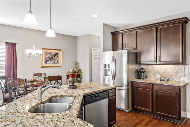 kitchen with sink, light stone counters, stainless steel appliances, and pendant lighting