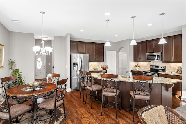 kitchen with appliances with stainless steel finishes, pendant lighting, backsplash, and light stone counters