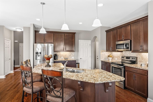 kitchen featuring decorative light fixtures, an island with sink, a kitchen breakfast bar, and stainless steel appliances