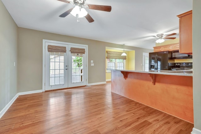 kitchen with pendant lighting, black appliances, french doors, light wood-type flooring, and a breakfast bar area