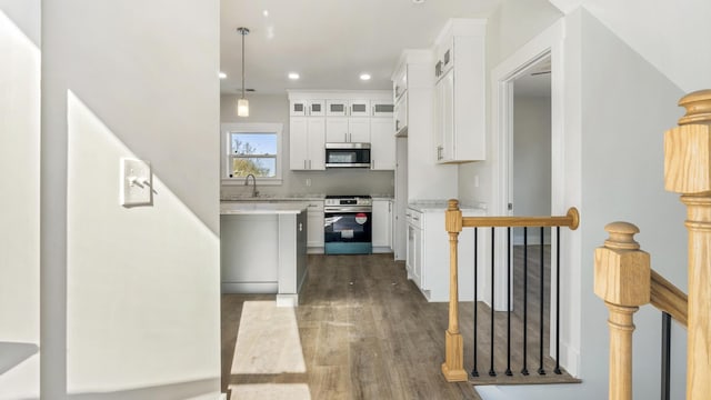 kitchen featuring hanging light fixtures, sink, stainless steel appliances, and white cabinetry