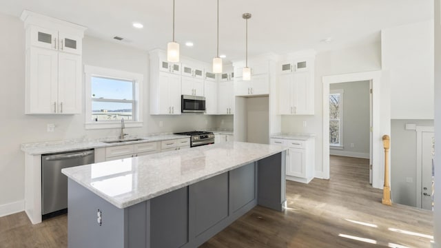 kitchen featuring white cabinets, appliances with stainless steel finishes, sink, and a kitchen island