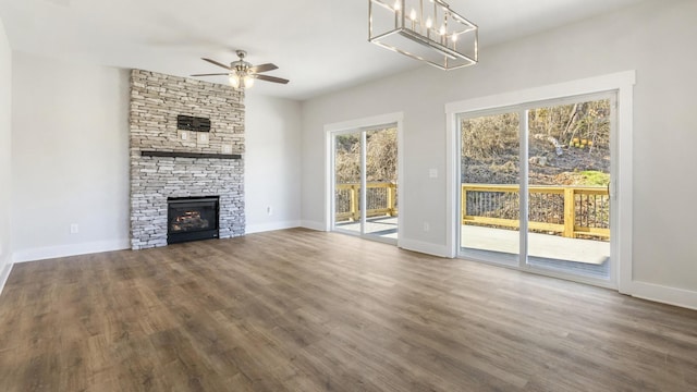 unfurnished living room with ceiling fan, dark hardwood / wood-style floors, and a stone fireplace