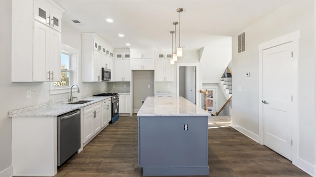 kitchen featuring a kitchen island, sink, white cabinetry, hanging light fixtures, and appliances with stainless steel finishes