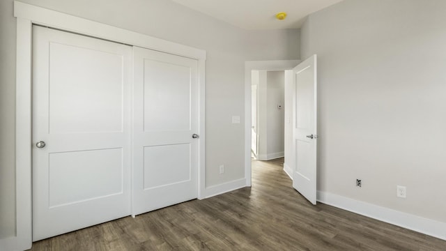 unfurnished bedroom with a closet and dark hardwood / wood-style flooring