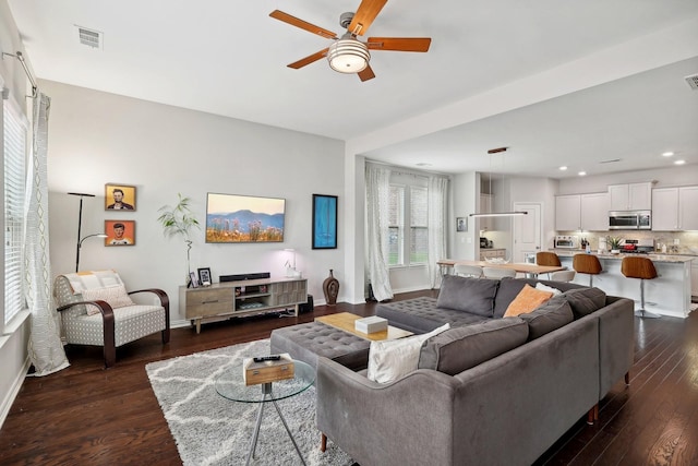 living room with ceiling fan and dark wood-type flooring