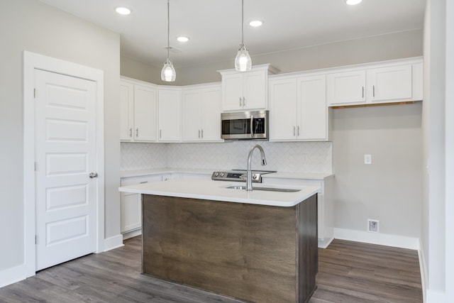 kitchen featuring a center island with sink, decorative light fixtures, dark hardwood / wood-style flooring, white cabinets, and sink