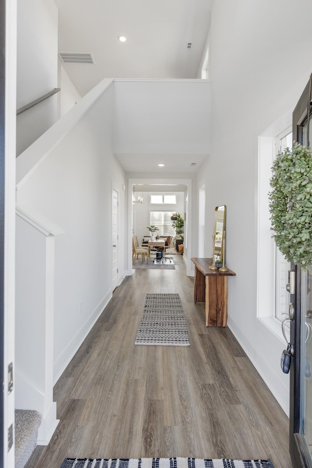 foyer featuring baseboards, a high ceiling, visible vents, and wood finished floors