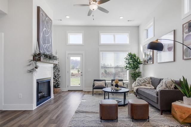 living room featuring a towering ceiling, a fireplace, baseboards, and dark wood-type flooring