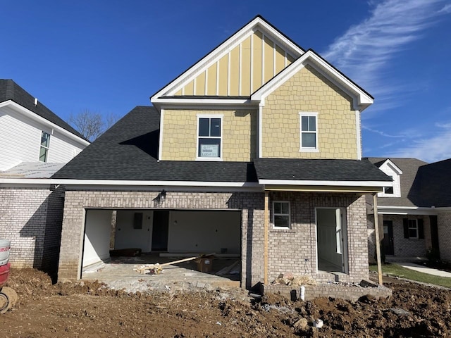 view of front of property featuring a shingled roof, board and batten siding, and brick siding