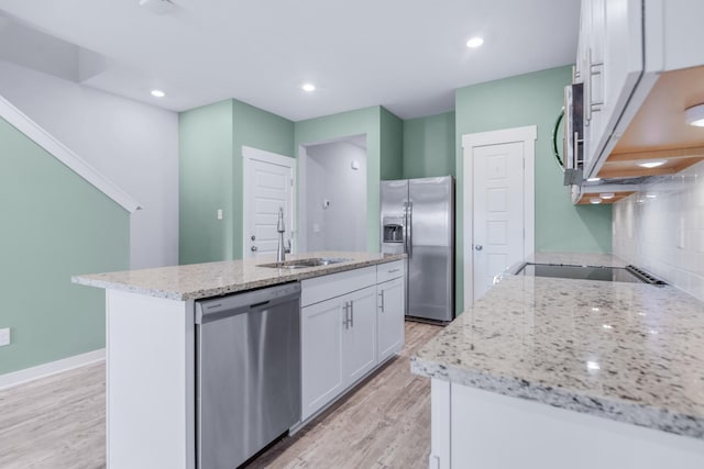 kitchen with appliances with stainless steel finishes, white cabinetry, an island with sink, sink, and backsplash