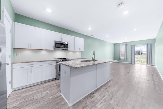 kitchen featuring white cabinets, appliances with stainless steel finishes, sink, and a kitchen island with sink