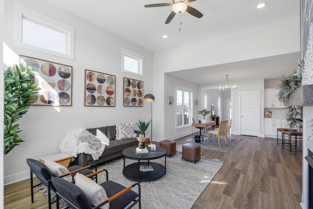 living room featuring ceiling fan with notable chandelier, dark wood-type flooring, and a high ceiling