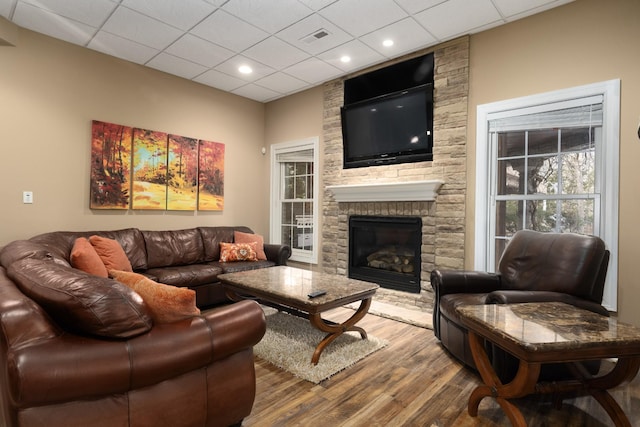 living room with a drop ceiling, a fireplace, and hardwood / wood-style floors