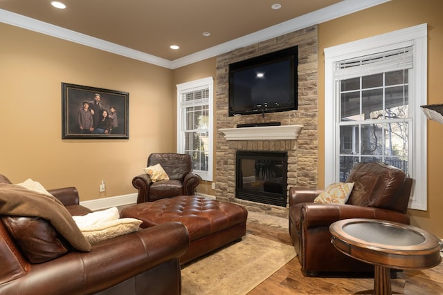 living room with crown molding, a stone fireplace, and light hardwood / wood-style floors