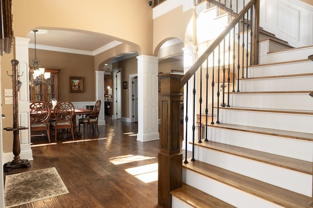 staircase with hardwood / wood-style flooring, ornamental molding, and a notable chandelier