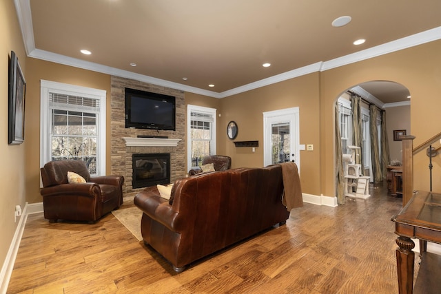 living room featuring light wood-type flooring, a fireplace, and crown molding